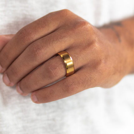 טבעת קלאסית מוזהבת לגבר "ראלי" מסטיינלס סטיל על הקמיצה של דוגמן יד שמאל זום רק על היד מוצמדת לבטן